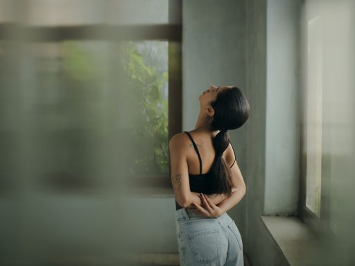 A woman leaning against a wall with her head in her hands