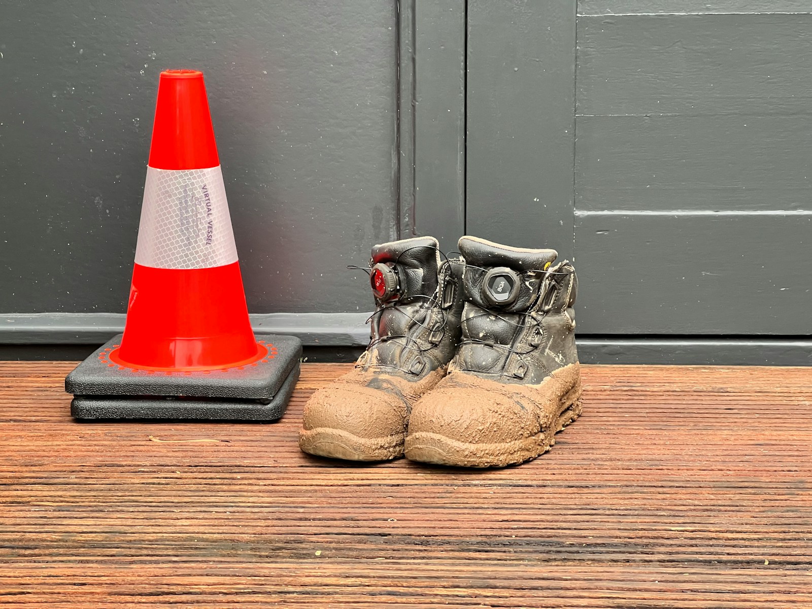 A pair of shoes sitting next to a traffic cone