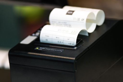 Kassamedewerker in een winkel die een kassabon uitprint aan de kassa