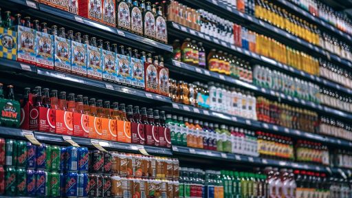 Een stagiair in een winkel die producten opstelt onder begeleiding van een winkeleigenaar